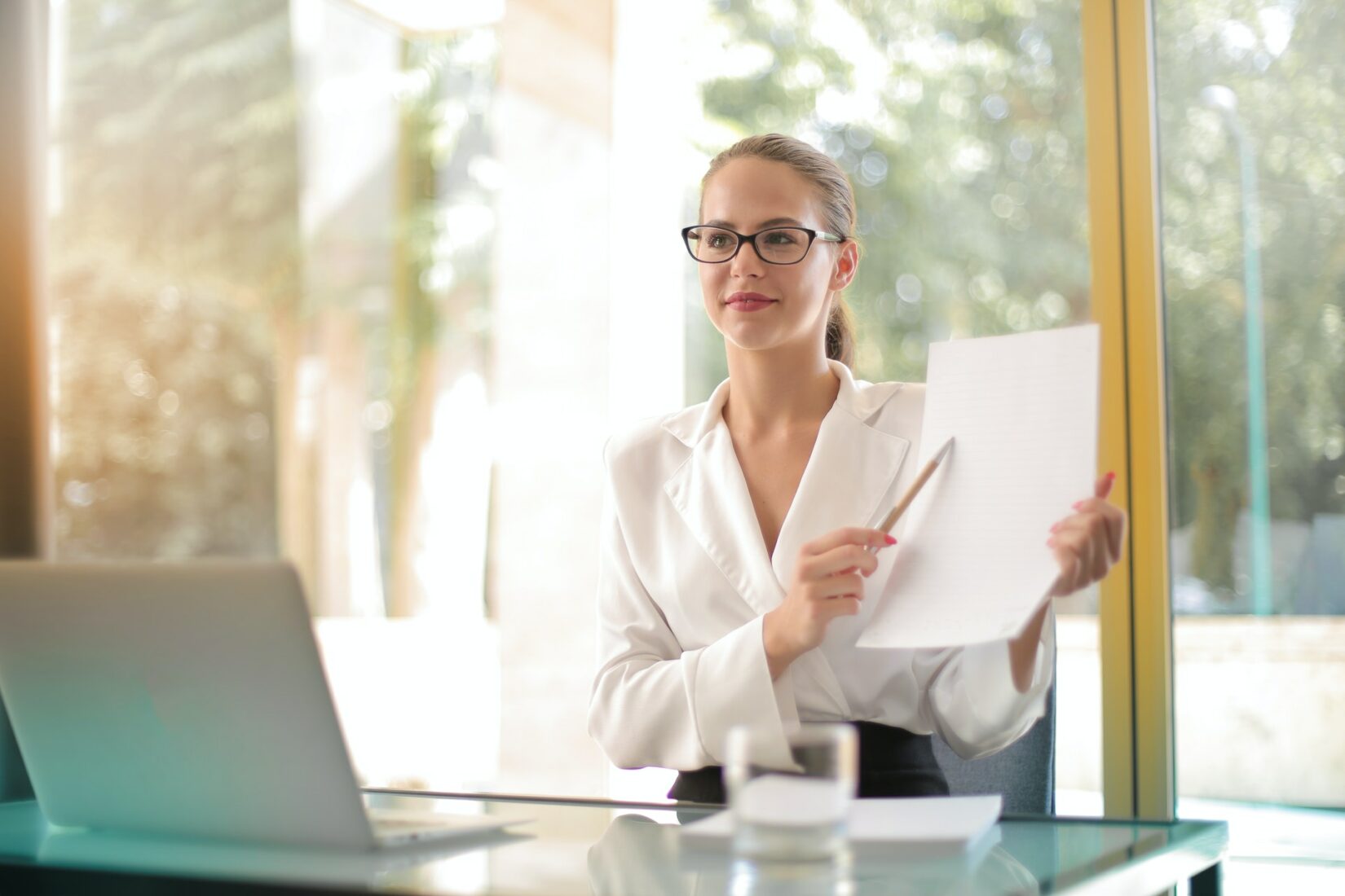 Woman presenting a document in front of a laptop