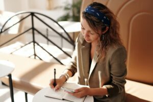 Woman holding her phone and writing on notebook