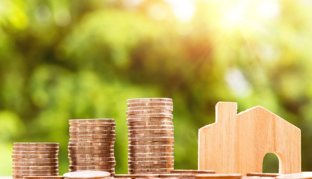 Stacks of coins beside a wood carved house