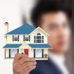 Selective focus of man holding a miniature house
