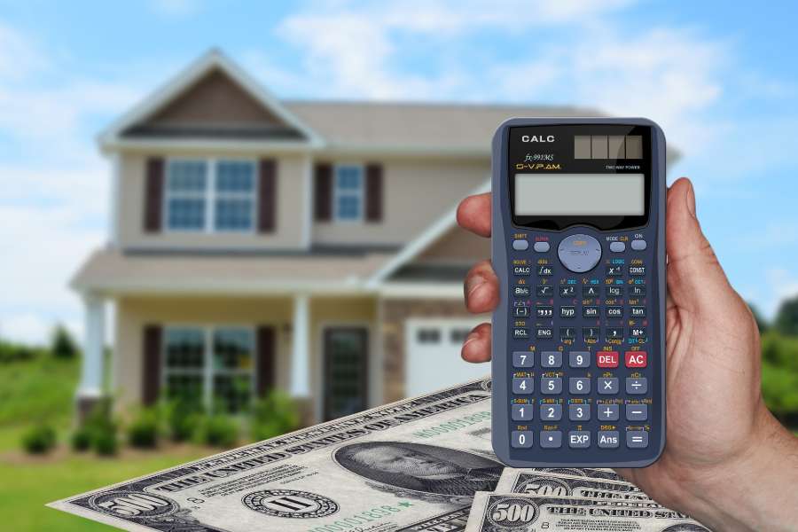 Hand holding a calculator to compute realtor fees and closing costs