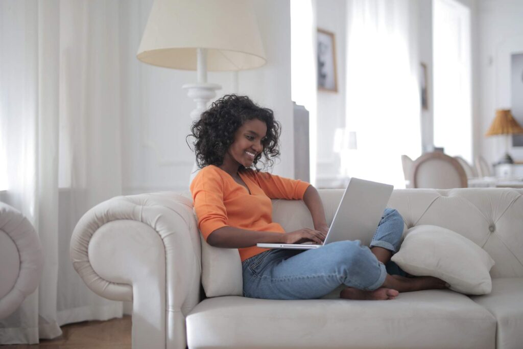 Woman sitting on a white couch while using a laptop