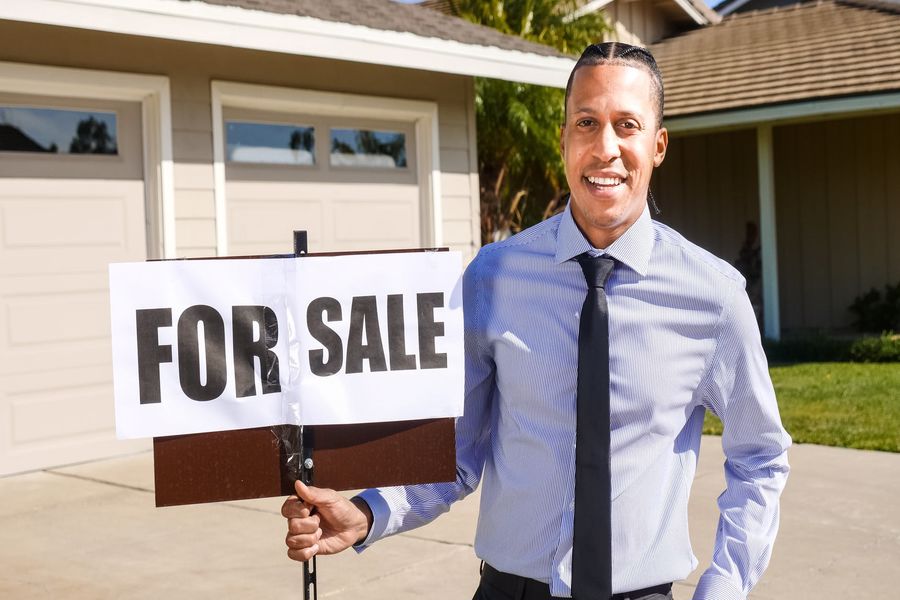 Real estate agent holding a For Sale sign