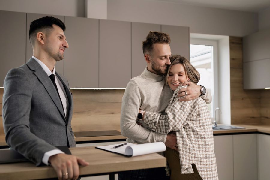 Couple hugging after signing house contract with a realtor