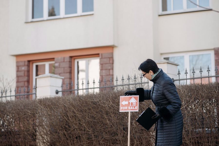 Realtor putting a for sale sign for a house