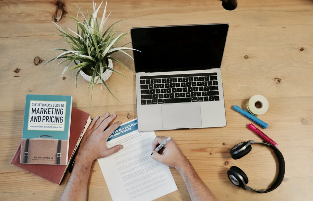 a laptop, headphones, books and several real estate resources on a table