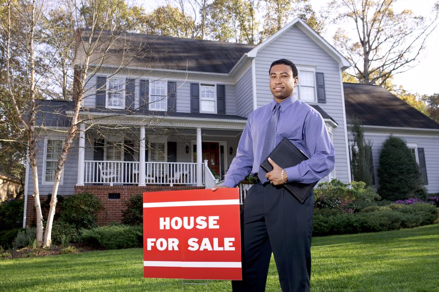 Real estate agent with house for sale sign