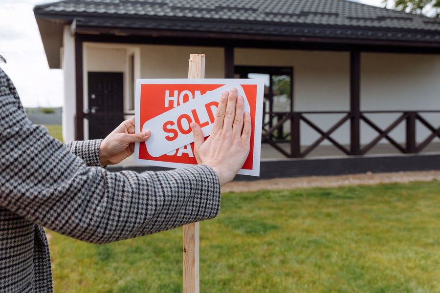 Person putting a sold sign on a wooden post