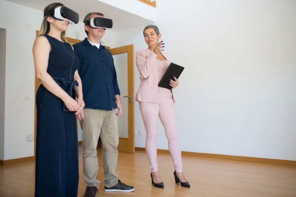 Realtor holding a black folder showing a couple who are both wearing VR headsets an empty property with white walls and wooden finishing