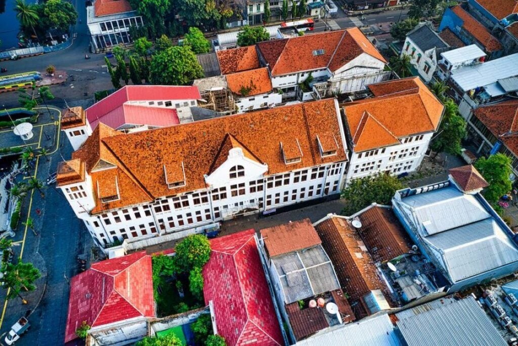 Aerial view of a building with an orange roof and white painted facade