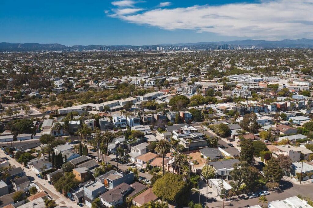 Drone shot of a neighborhood with their multi colored roofs, green trees and street structure visible from view