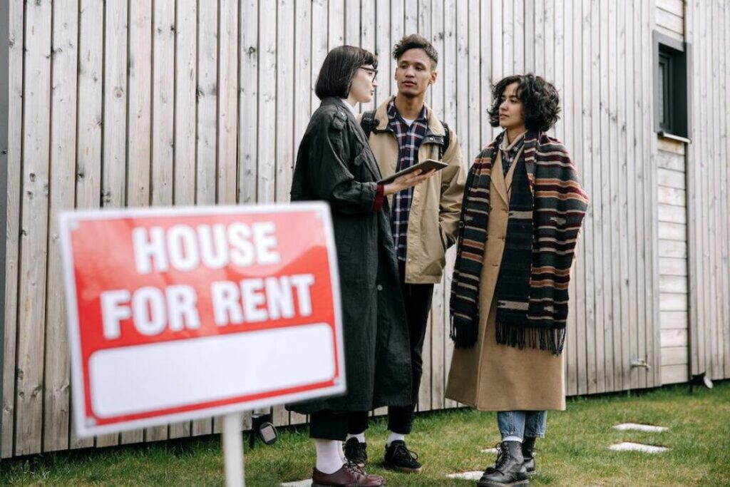 Realtor talking to a couple who are looking to rent a house with a natural wooden facade