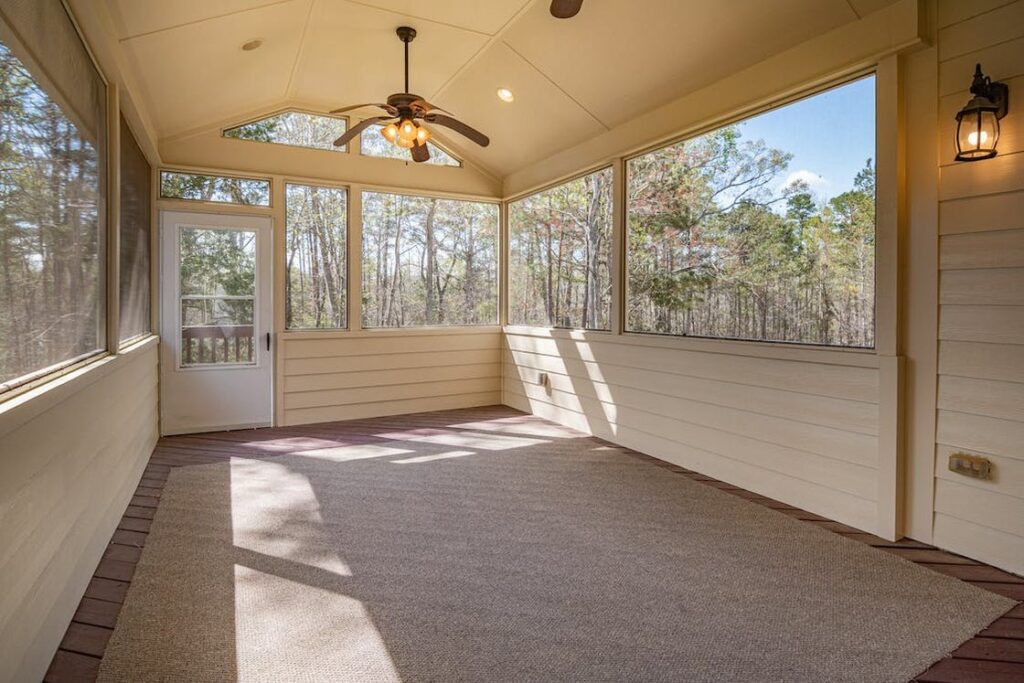 Ceiling fan hanging on a white painted empty room that has a light brown colored rug on the floor