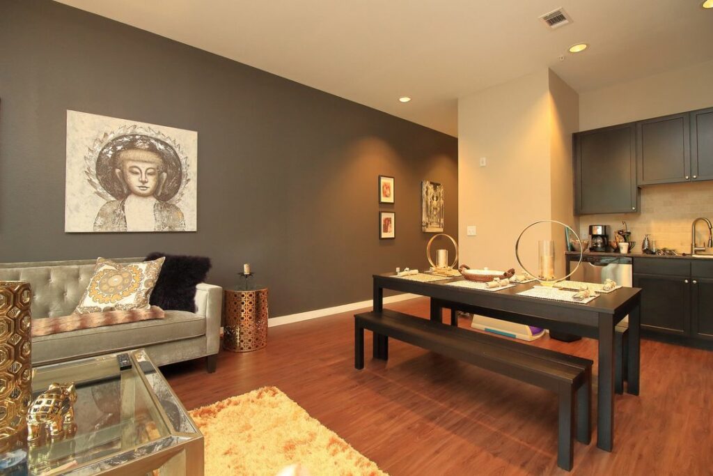 Gray colored walls of a living room area combined with a black dining table and kitchen