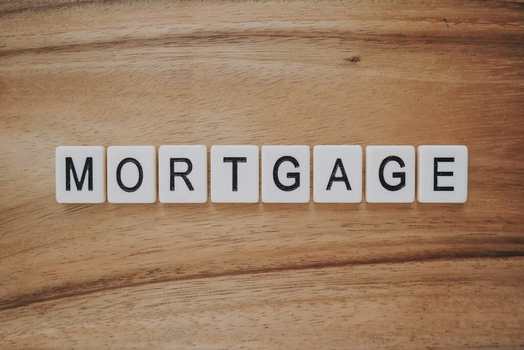 Scrabble tiles on a wooden table spelling the word "mortgage"